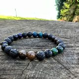 Bracelet Akira avec 7 différents pierres semi-précieuses : oeil de tigre, oeil de boeuf, oeil de tigre violet et oeil de tigre vert, oeil de faucon, pierre de lava et onyx noir brillant.