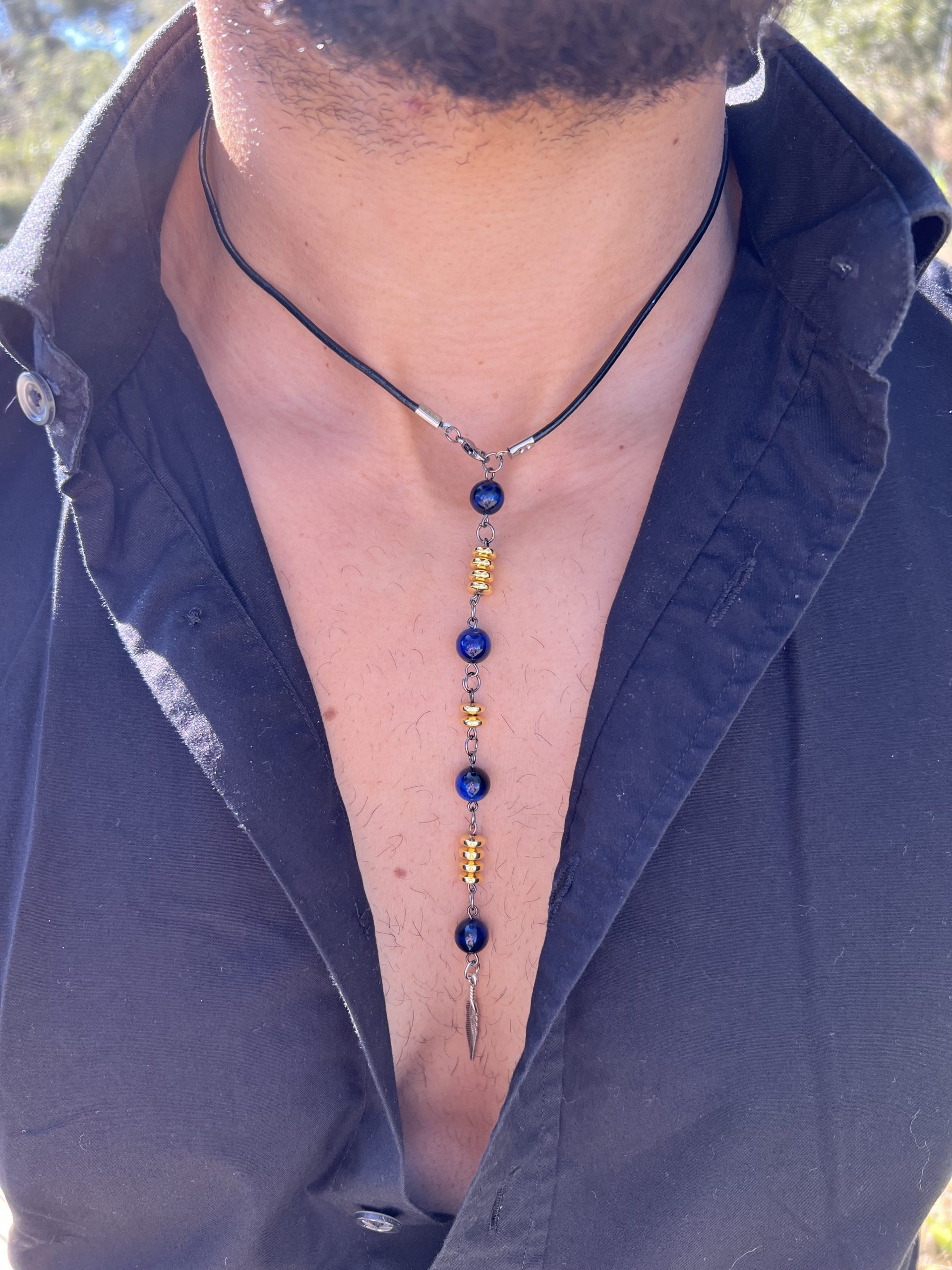 Collier Via avec l'oeil de tigre beu de lapis lazuli, oeil de tigre bleu foncé, les entretoises dorées et plume agentée