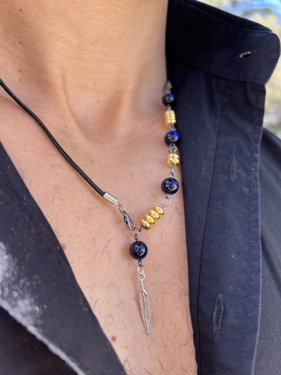 Collier Via avec l'oeil de tigre beu de lapis lazuli, oeil de tigre bleu foncé, les entretoises dorées et plume agentée