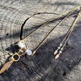 Découvrez le Collier Soe Ari une pièce de bijouterie exceptionnelle qui allie élégance, polyvalence et bienfaits énergétiques. Conçu par Jana Kuzmi, artiste peintre et fondatrice de la marque Boucle Bel Air, ce collier ajustable en longueur offre une infinité de possibilités de style. Grâce à sa perle coulissante, il peut être porté en ras de cou, en collier classique ou en sautoir, s'adaptant ainsi à toutes les occasions et à tous les looks. Collier Soe Ari se distingue par son design ingénieux qui permet de le porter à l'envers, offrant ainsi une toute nouvelle esthétique. Doté d'un pendentif composé de perles et de fines perles en coquillages suspendues et ornées d'une plume dorée, ce bijou est une véritable œuvre d'art. De plus, les finitions du dos du collier, avec deux chaînes ornées de plumes dorées et de perles d'agate blanches plus petites, ajoutent une touche de sophistication et de raffinement. Mais le Collier Soe Ari ne se contente pas d'être beau, il offre également des bienfaits sur le plan énergétique grâce à l'agate blanche. Connue pour ses propriétés de guérison et d'équilibre, l'agate blanche aide à dissiper le stress et à favoriser un sentiment de calme intérieur. En portant ce collier, vous bénéficiez donc non seulement d'un accessoire de mode exceptionnel, mais aussi d'un véritable allié pour votre bien-être. Fabriqué avec soin à partir d'agate blanche brillante, de perles plates polies en coquillages et d'une chaîne en acier inoxydable doré, le Collier Soe Ari incarne le savoir-faire artisanal et la qualité supérieure. Chaque détail a été pensé pour offrir une expérience unique à celui ou celle qui le porte.Offrez-vous dès maintenant le plaisir de posséder un bijou aussi spécial que vous avec le Collier Soe Ari. Que ce soit pour une occasion spéciale ou pour égayer votre tenue quotidienne, ce collier polyvalent saura vous accompagner avec style et élégance.