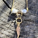 Découvrez le Collier Soe Ari une pièce de bijouterie exceptionnelle qui allie élégance, polyvalence et bienfaits énergétiques. Conçu par Jana Kuzmi, artiste peintre et fondatrice de la marque Boucle Bel Air, ce collier ajustable en longueur offre une infinité de possibilités de style. Grâce à sa perle coulissante, il peut être porté en ras de cou, en collier classique ou en sautoir, s'adaptant ainsi à toutes les occasions et à tous les looks. Collier Soe Ari se distingue par son design ingénieux qui permet de le porter à l'envers, offrant ainsi une toute nouvelle esthétique. Doté d'un pendentif composé de perles et de fines perles en coquillages suspendues et ornées d'une plume dorée, ce bijou est une véritable œuvre d'art. De plus, les finitions du dos du collier, avec deux chaînes ornées de plumes dorées et de perles d'agate blanches plus petites, ajoutent une touche de sophistication et de raffinement. Mais le Collier Soe Ari ne se contente pas d'être beau, il offre également des bienfaits sur le plan énergétique grâce à l'agate blanche. Connue pour ses propriétés de guérison et d'équilibre, l'agate blanche aide à dissiper le stress et à favoriser un sentiment de calme intérieur. En portant ce collier, vous bénéficiez donc non seulement d'un accessoire de mode exceptionnel, mais aussi d'un véritable allié pour votre bien-être. Fabriqué avec soin à partir d'agate blanche brillante, de perles plates polies en coquillages et d'une chaîne en acier inoxydable doré, le Collier Soe Ari incarne le savoir-faire artisanal et la qualité supérieure. Chaque détail a été pensé pour offrir une expérience unique à celui ou celle qui le porte.Offrez-vous dès maintenant le plaisir de posséder un bijou aussi spécial que vous avec le Collier Soe Ari. Que ce soit pour une occasion spéciale ou pour égayer votre tenue quotidienne, ce collier polyvalent saura vous accompagner avec style et élégance.