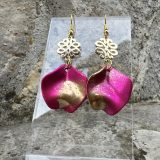 Boucles d’oreilles Flavie Découvrez les boucles d’oreilles “Flavie”, des bijoux fantaisie uniques en leur genre. Déclinées en plusieurs couleurs tendance  – blanc mat, rose métallisé, vert foncé métallisé, bleu royal mat, rouge métallisé et or – elles offrent une touche de raffinement avec leurs projections de couleur or, appliquées à la main pour une finition singulière sur chaque paire. Le design inclut un élément doré élégant et une pétale suspendue de couleur tachetée or, rendant ces boucles d’oreilles idéales pour compléter vos tenues au quotidien ou pour des occasions spéciales. Créées par l’artiste Jana Kuzmi, elles représentent un accessoire original et de qualité qui saura se démarquer dans votre collection de bijoux.