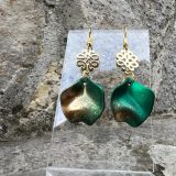 Boucles d’oreilles Flavie Découvrez les boucles d’oreilles “Flavie”, des bijoux fantaisie uniques en leur genre. Déclinées en plusieurs couleurs tendance  – blanc mat, rose métallisé, vert foncé métallisé, bleu royal mat, rouge métallisé et or – elles offrent une touche de raffinement avec leurs projections de couleur or, appliquées à la main pour une finition singulière sur chaque paire. Le design inclut un élément doré élégant et une pétale suspendue de couleur tachetée or, rendant ces boucles d’oreilles idéales pour compléter vos tenues au quotidien ou pour des occasions spéciales. Créées par l’artiste Jana Kuzmi, elles représentent un accessoire original et de qualité qui saura se démarquer dans votre collection de bijoux.