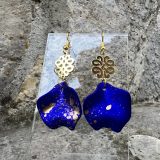 Boucles d’oreilles Flavie Découvrez les boucles d’oreilles “Flavie”, des bijoux fantaisie uniques en leur genre. Déclinées en plusieurs couleurs tendance  – blanc mat, rose métallisé, vert foncé métallisé, bleu royal mat, rouge métallisé et or – elles offrent une touche de raffinement avec leurs projections de couleur or, appliquées à la main pour une finition singulière sur chaque paire. Le design inclut un élément doré élégant et une pétale suspendue de couleur tachetée or, rendant ces boucles d’oreilles idéales pour compléter vos tenues au quotidien ou pour des occasions spéciales. Créées par l’artiste Jana Kuzmi, elles représentent un accessoire original et de qualité qui saura se démarquer dans votre collection de bijoux.