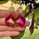 Boucles d’oreilles Flavie Découvrez les boucles d’oreilles “Flavie”, des bijoux fantaisie uniques en leur genre. Déclinées en plusieurs couleurs tendance  – blanc mat, rose métallisé, vert foncé métallisé, bleu royal mat, rouge métallisé et or – elles offrent une touche de raffinement avec leurs projections de couleur or, appliquées à la main pour une finition singulière sur chaque paire. Le design inclut un élément doré élégant et une pétale suspendue de couleur tachetée or, rendant ces boucles d’oreilles idéales pour compléter vos tenues au quotidien ou pour des occasions spéciales. Créées par l’artiste Jana Kuzmi, elles représentent un accessoire original et de qualité qui saura se démarquer dans votre collection de bijoux.