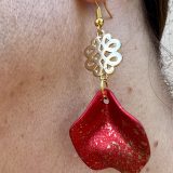 Boucles d’oreilles Flavie Découvrez les boucles d’oreilles “Flavie”, des bijoux fantaisie uniques en leur genre. Déclinées en plusieurs couleurs tendance  – blanc mat, rose métallisé, vert foncé métallisé, bleu royal mat, rouge métallisé et or – elles offrent une touche de raffinement avec leurs projections de couleur or, appliquées à la main pour une finition singulière sur chaque paire. Le design inclut un élément doré élégant et une pétale suspendue de couleur tachetée or, rendant ces boucles d’oreilles idéales pour compléter vos tenues au quotidien ou pour des occasions spéciales. Créées par l’artiste Jana Kuzmi, elles représentent un accessoire original et de qualité qui saura se démarquer dans votre collection de bijoux.