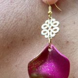 Boucles d’oreilles Flavie Découvrez les boucles d’oreilles “Flavie”, des bijoux fantaisie uniques en leur genre. Déclinées en plusieurs couleurs tendance  – blanc mat, rose métallisé, vert foncé métallisé, bleu royal mat, rouge métallisé et or – elles offrent une touche de raffinement avec leurs projections de couleur or, appliquées à la main pour une finition singulière sur chaque paire. Le design inclut un élément doré élégant et une pétale suspendue de couleur tachetée or, rendant ces boucles d’oreilles idéales pour compléter vos tenues au quotidien ou pour des occasions spéciales. Créées par l’artiste Jana Kuzmi, elles représentent un accessoire original et de qualité qui saura se démarquer dans votre collection de bijoux.