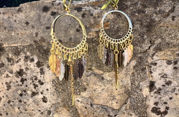 Boucles d'oreilles - Attrape rêve Boucles d'oreilles artisanales avec plumes colorées/teintes dorées et argentées – Attrape-rêves fait main par Jana Kuzmi | Boucle Bel Air Découvrez nos magnifiques boucles d'oreilles artisanales, conçues avec soin par l'artiste Jana Kuzmi sous la marque Boucle Bel Air. Chaque paire met en valeur des plumes dures de différentes couleurs, attachées à un cercle qui forme un attrape-rêves unique et élégant. Parfaites pour ajouter une touche bohème et colorée à votre style, ces boucles d'oreilles faites main sont idéales pour les amoureux de l'artisanat et de la mode éthique. Boucles d'oreilles - Attrape rêve Offrez-vous un accessoire original, léger et plein de charme, qui reflète la créativité et le savoir-faire de Jana Kuzmi. Caractéristiques principales : Création artisanale par Jana Kuzmi Design attrape-rêves avec plumes colorées Boucles d'oreilles faites main Matériaux de qualité, plumes dures résistantes Idéal pour un style bohème, ethnique ou tendance Ajoutez une touche d'originalité à votre collection avec ces, Boucles d'oreilles - Attrape rêve, uniques, parfaites pour toutes les occasions. 