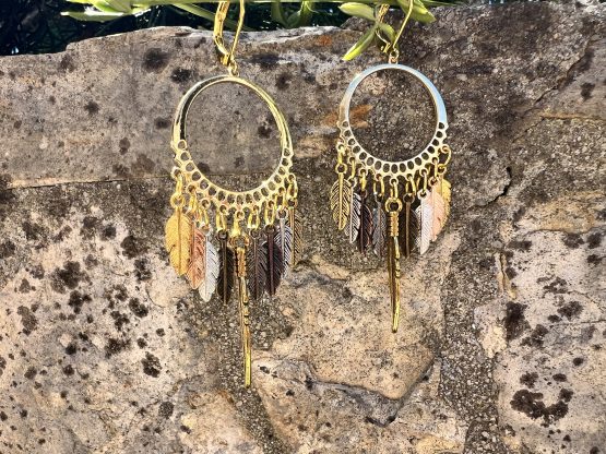 Boucles d'oreilles - Attrape rêve Boucles d'oreilles artisanales avec plumes colorées/teintes dorées et argentées – Attrape-rêves fait main par Jana Kuzmi | Boucle Bel Air Découvrez nos magnifiques boucles d'oreilles artisanales, conçues avec soin par l'artiste Jana Kuzmi sous la marque Boucle Bel Air. Chaque paire met en valeur des plumes dures de différentes couleurs, attachées à un cercle qui forme un attrape-rêves unique et élégant. Parfaites pour ajouter une touche bohème et colorée à votre style, ces boucles d'oreilles faites main sont idéales pour les amoureux de l'artisanat et de la mode éthique. Boucles d'oreilles - Attrape rêve Offrez-vous un accessoire original, léger et plein de charme, qui reflète la créativité et le savoir-faire de Jana Kuzmi. Caractéristiques principales : Création artisanale par Jana Kuzmi Design attrape-rêves avec plumes colorées Boucles d'oreilles faites main Matériaux de qualité, plumes dures résistantes Idéal pour un style bohème, ethnique ou tendance Ajoutez une touche d'originalité à votre collection avec ces, Boucles d'oreilles - Attrape rêve, uniques, parfaites pour toutes les occasions. 