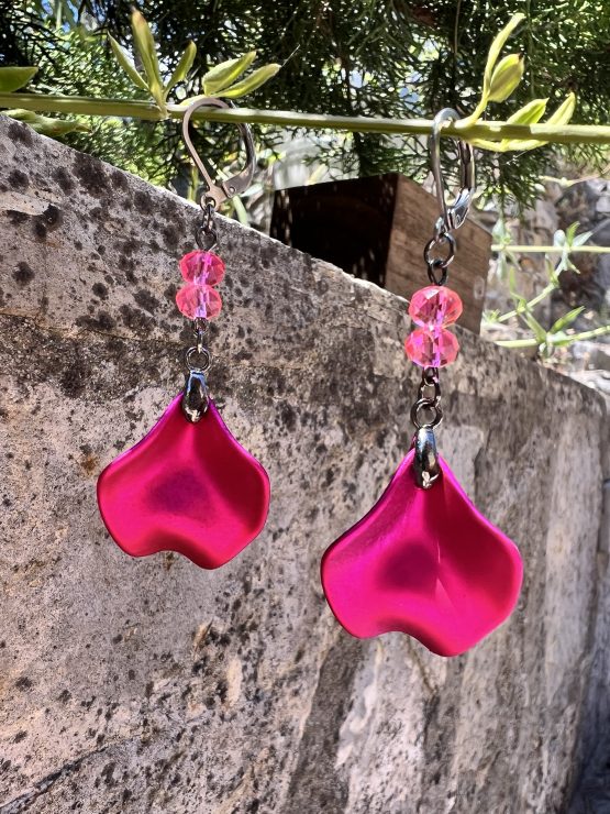 Boucles d'oreilles avec pétale rose métallisée et perles roses – Création de Jana Kuzmi pour Boucle Bel Air Apportez une touche de douceur et d'élégance à votre style avec ces magnifiques boucles d'oreilles pendantes, entièrement faites main par l'artiste peintre et créatrice de bijoux Jana Kuzmi, sous la marque Boucle Bel Air. Chaque paire se distingue par une pétale en métal rose métallisé, délicatement travaillée pour refléter la lumière et créer un effet sophistiqué. Suspendues à une attache sécurisée en acier inoxydable gris foncé, elles offrent à la fois confort et durabilité. Deux perles roses suspendues viennent compléter l'ensemble, apportant une note de féminité et de romantisme à ces bijoux uniques. Leur design bohème chic en fait un accessoire parfait pour sublimer vos tenues lors d'événements spéciaux ou pour une allure quotidienne élégante. Boucles d'oreilles avec pétale rose métallisée et perles roses Caractéristiques principales : Création artisanale par Jana Kuzmi Boucles d'oreilles pendantes en métal rose métallisé Deux perles roses suspendues pour une touche raffinée Attache sécurisée en acier inoxydable gris foncé, hypoallergénique et résistante Style bohème chic, fait main, idéal pour une allure élégante et tendance Offrez-vous ou offrez à un proche cette pièce unique, symbole de créativité et de savoir-faire artisanal. Un bijou qui allie finesse, originalité et élégance, signé par l’artiste Jana Kuzmi et présenté par Boucle Bel Air.