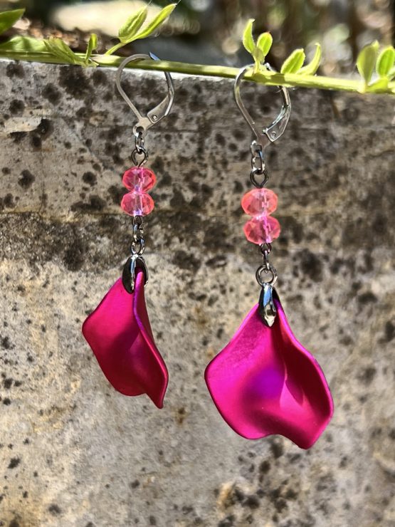 Boucles d'oreilles avec pétale rose métallisée et perles roses – Création de Jana Kuzmi pour Boucle Bel Air Apportez une touche de douceur et d'élégance à votre style avec ces magnifiques boucles d'oreilles pendantes, entièrement faites main par l'artiste peintre et créatrice de bijoux Jana Kuzmi, sous la marque Boucle Bel Air. Chaque paire se distingue par une pétale en métal rose métallisé, délicatement travaillée pour refléter la lumière et créer un effet sophistiqué. Suspendues à une attache sécurisée en acier inoxydable gris foncé, elles offrent à la fois confort et durabilité. Deux perles roses suspendues viennent compléter l'ensemble, apportant une note de féminité et de romantisme à ces bijoux uniques. Leur design bohème chic en fait un accessoire parfait pour sublimer vos tenues lors d'événements spéciaux ou pour une allure quotidienne élégante. Boucles d'oreilles avec pétale rose métallisée et perles roses Caractéristiques principales : Création artisanale par Jana Kuzmi Boucles d'oreilles pendantes en métal rose métallisé Deux perles roses suspendues pour une touche raffinée Attache sécurisée en acier inoxydable gris foncé, hypoallergénique et résistante Style bohème chic, fait main, idéal pour une allure élégante et tendance Offrez-vous ou offrez à un proche cette pièce unique, symbole de créativité et de savoir-faire artisanal. Un bijou qui allie finesse, originalité et élégance, signé par l’artiste Jana Kuzmi et présenté par Boucle Bel Air.