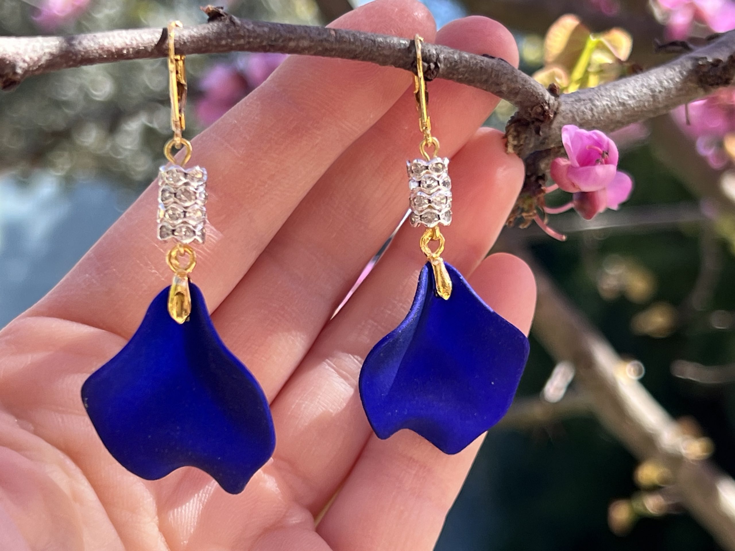 Boucles d’oreilles bleu royal « Blue nuit » — Création de Jana KUZMI Boucles d’oreilles pendantes bleu royal et dorées, ornées de zircons transparents — création originale réalisée à la main par Jana KUZMI. Laissez-vous séduire par « Blue », une paire de boucles d’oreilles lumineuse et élégante, imaginée et réalisée à la main par l’artiste Jana KUZMI. 💙 Leurs pétales bleu royal métallisé révèlent de subtils reflets à chaque mouvement et donnent à la création une présence raffinée et contemporaine. Les entretoises délicatement ornées de zircons transparents captent la lumière et viennent souligner l’intensité du bleu. Les boucles sont montées sur des attaches sécurisées en acier inoxydable doré, pour associer élégance, confort et maintien. ✨ Une touche de bleu qui attire le regard Profond et vibrant, le bleu royal apporte une note sophistiquée et originale à toutes les tenues. « Blue » s’adresse aux femmes qui aiment les bijoux de caractère, élégants mais différents. Parfaites pour une tenue habillée comme pour apporter une touche précieuse à un look quotidien, ces boucles d’oreilles deviennent facilement la pièce qui attire les regards. Chaque paire est réalisée à la main par Jana KUZMI, dans une démarche créative où le bijou devient une véritable expression artistique. « Blue » — l’intensité du bleu, l’éclat de l’or, la lumière d’un bijou unique. 💙✨ Caractéristiques : Boucles d’oreilles pendantes Création originale réalisée à la main Pétales bleu royal métallisé Entretoises ornées de zircons transparents Attaches sécurisées Acier inoxydable finition dorée Création signée Jana KUZMI Bijou original, élégant et contemporain